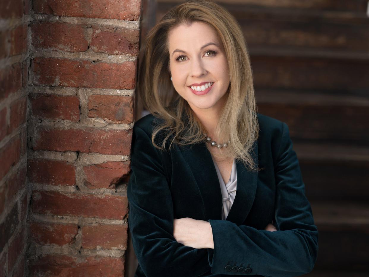 Michelle Bond poses in front of a brick wall.