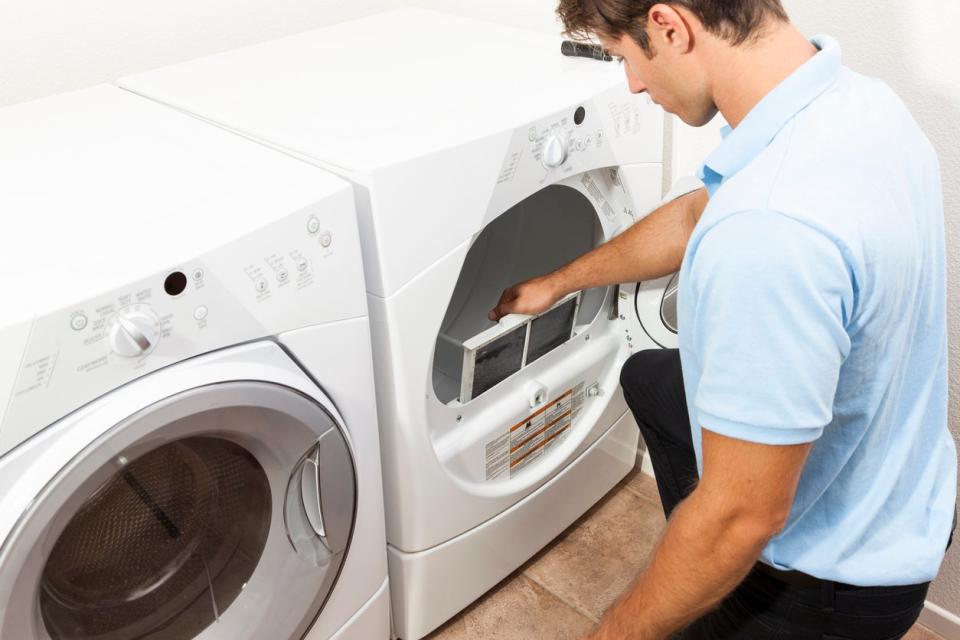 Man cleaning dryer vent and filter in home.