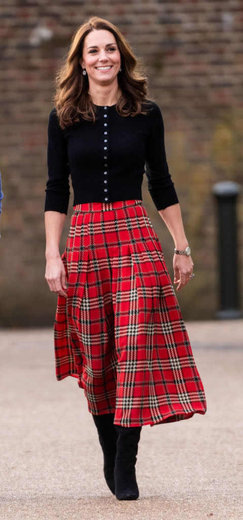 Kate Middleton wears a black cardigan and red tartan skirt by Emilia Wickstead to host a Christmas party with Prince William on Dec. 4 at Kensington Palace. (Photo: Mark Cuthbert/Getty Images)