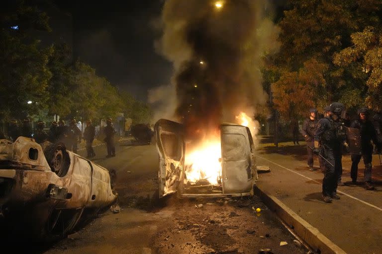 Police forces walk past burning cars in Nanterre, outside Paris, Thursday, June 29, 2023. The death of 17-year-old Nael by police during a traffic check Tuesday in the Paris suburb of Nanterre elicited nationwide concern and widespread messages of indignation and condolences. Interior Minister Gerald Darmanin said 1,200 police were deployed overnight and 2,000 would be out in force Wednesday in the Paris region and around other big cities to 