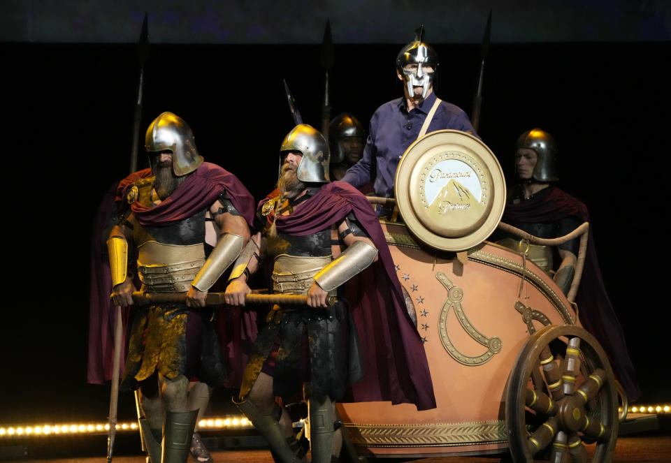 Chris Aronson, right, president of domestic theatrical distribution for Paramount Pictures, arrives via chariot to the Paramount Pictures presentation at CinemaCon 2024, Thursday, April 11, 2024, at Caesars Palace in Las Vegas. The studio is releasing "Gladiator 2" later in the year. (AP Photo/Chris Pizzello)