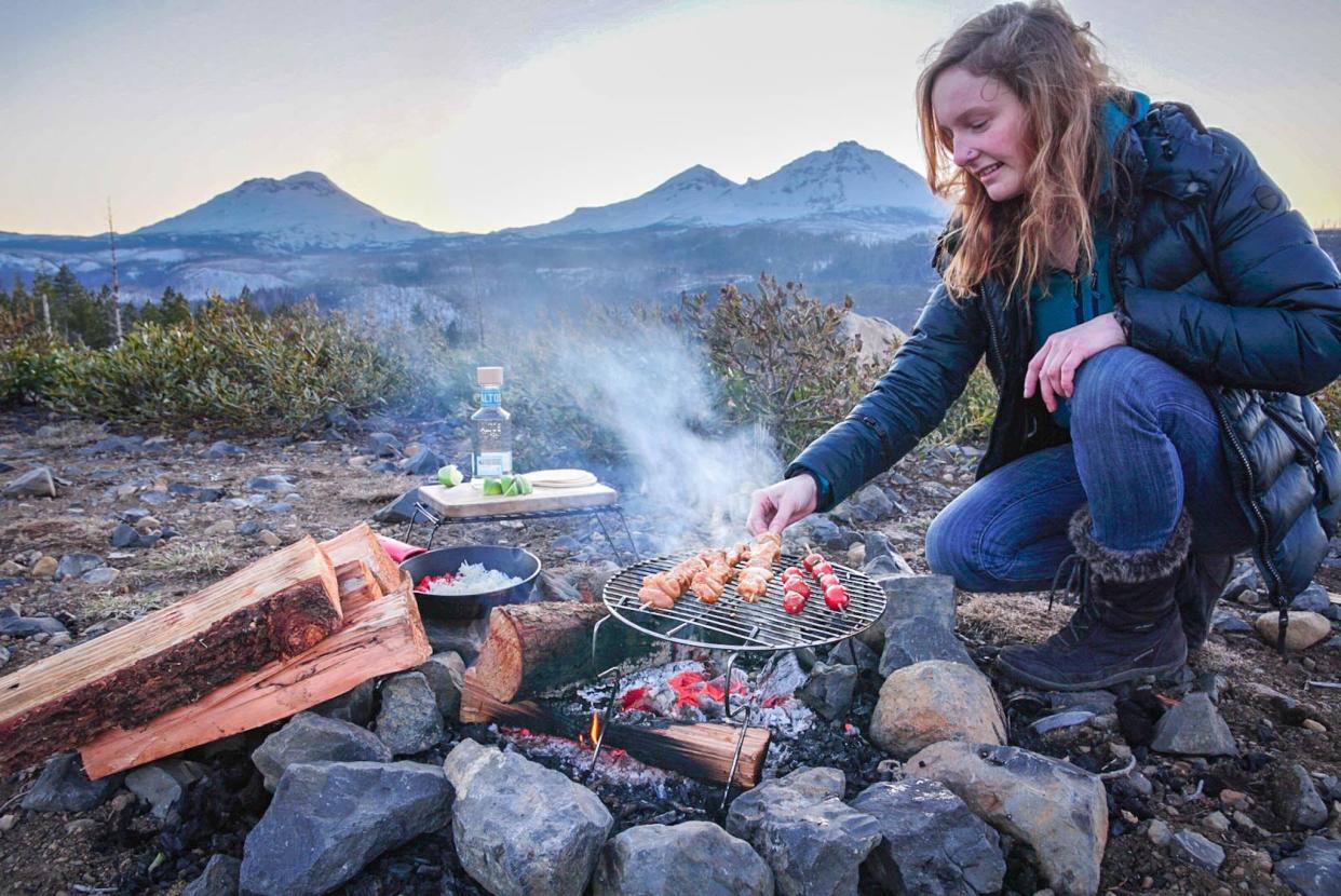 Wilderness chef and forager Kayla Sulak cooks up a meal over a campfire.