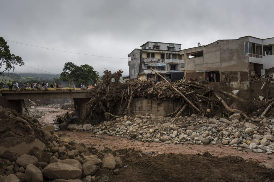 Displaced residents walk across a bridge over the Mocoa River after a landslide in Mocoa, Colombia, in 2017.  (Nicolo Filippo Rosso / Bloomberg via Getty Images)