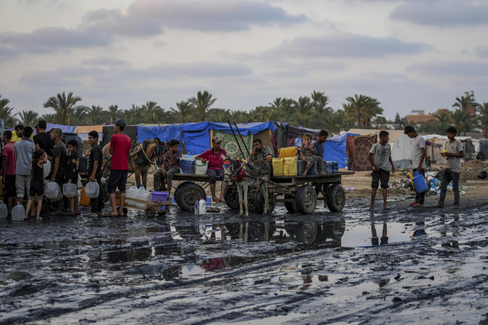 Palestinians gather to fill water jugs near one of the strip's few functioning desalination plants in Deir al-Balah, Gaza Strip, Thursday, June 20, 2024. Israel's war in Gaza has decimated the strip's sanitation system while simultaneously displacing the vast majority of the population, leaving many Palestinians living in tent camps nearby growing piles of garbage. (AP Photo/Abdel Kareem Hana)