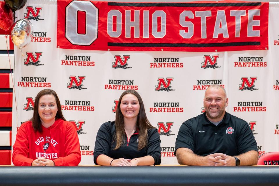 Norton High School senior Morgan Hallett, center, smiles with her parents, Jennifer and Brian, Wednesday after signing a national letter of intent to continue her track and field career at Ohio State University.