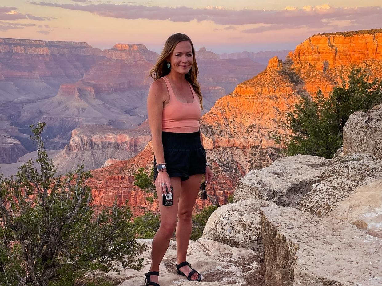 Emily standing in front of the Grand Canyon as the sun sets.