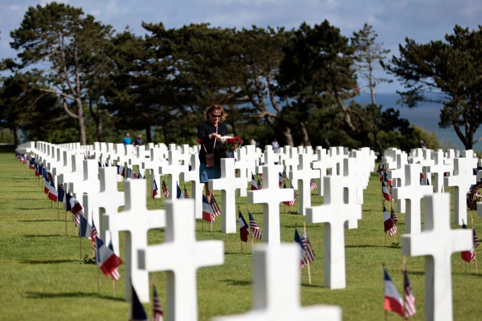 A woman holds a bouquet of roses during the 78th anniversary of D-Day ceremony  June, 6, 2022, in the Normandy American Cemetery and Memorial of Colleville-sur-Mer, overlooking Omaha Beach. The ceremonies pay tribute to the nearly 160,000 troops from Britain, the U.S., Canada and elsewhere who landed on French beaches on June 6, 1944, to restore freedom to Europe after Nazi occupation.