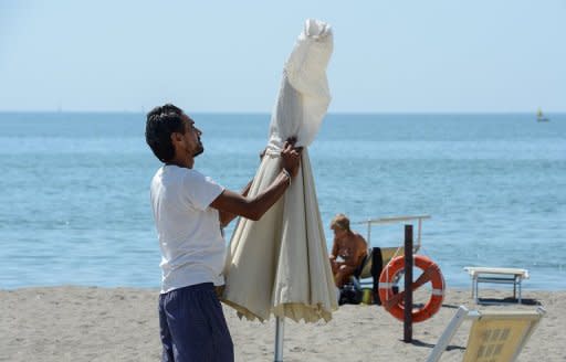 An employee folds a parasol at a private beach in Lido di Ostia near Rome. Thousands of Italy's private beaches have kept their parasols closed in peak summer season in a symbolic protest against a new European Union directive that could force many to shut down