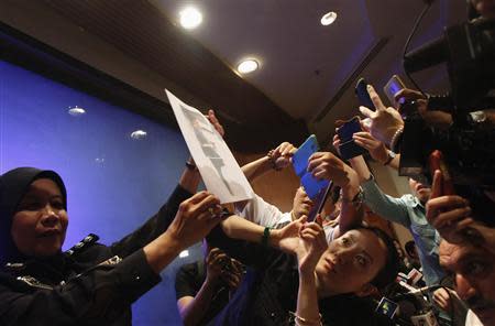 A policewoman holds up a photo of one of the two men whom they believe were travelling onboard the missing Malaysia Airlines MH370 on stolen passports after a news conference in Kuala Lumpur International Airport March 11, 2014. REUTERS/Edgar Su