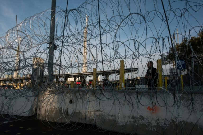 A US border control agent patrols the new barriers set up as a migrant caravan pours into Tijuana on the other side of the frontier