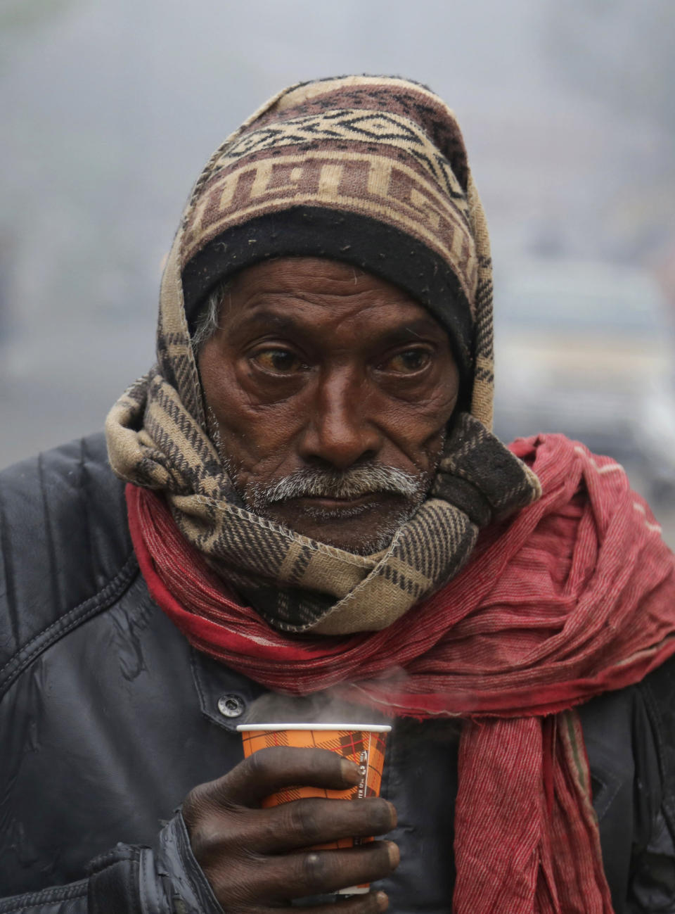 A man holds a hot cup of tea on a cold and foggy morning in Jammu, India, Tuesday, Dec. 31, 2019. Opaque, chilly smog has blanketed northern India as just-about-freezing temperatures collided with hazardous levels of air pollution. The cold and fog are expected to continue through New Year's Day. (AP Photo/Channi Anand)