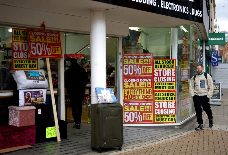 FILE PHOTO: A man walks past a shop with closing down signs in the window in Croydon