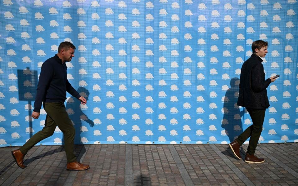 People walk past branding on the first day of the annual Conservative Party Conference in Birmingham - Paul Ellis/AFP