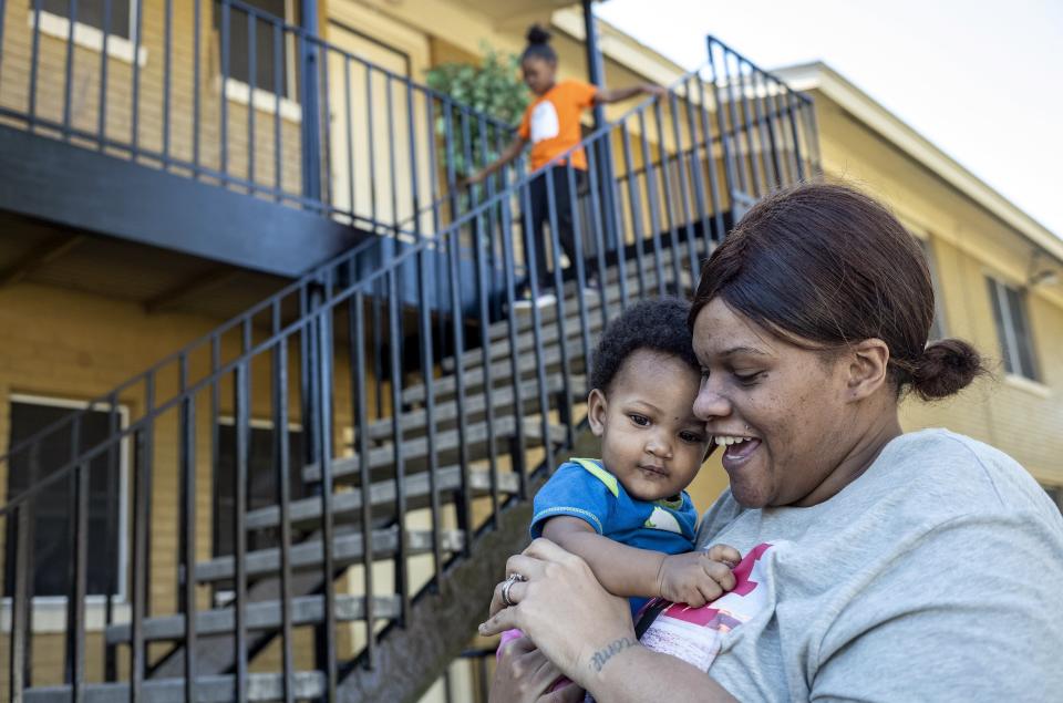 Ashley Joiner, 30, carries 9-month-old Gemirha Jerome outside the family's apartment. The family needs a bigger space as well as a vehicle in which everyone can fit.