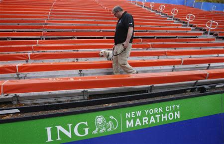 A security guard and bomb sniffing dog patrol grandstands in the area near the finish line of the New York City Marathon in New York's Central Park November 1, 2013. REUTERS/Mike Segar