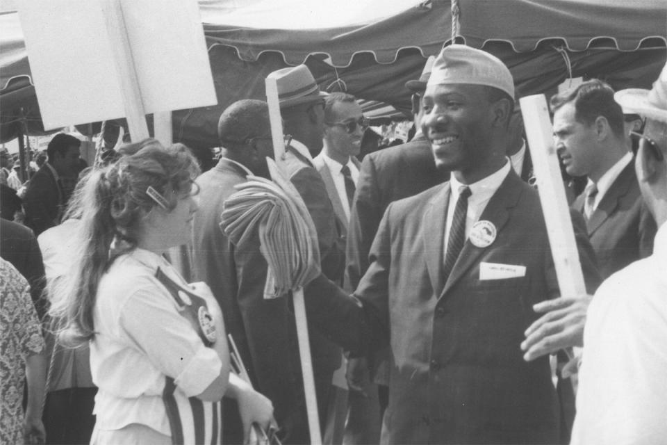 Several people of various races talk together, smiling, in a 1963 surveillance photo.