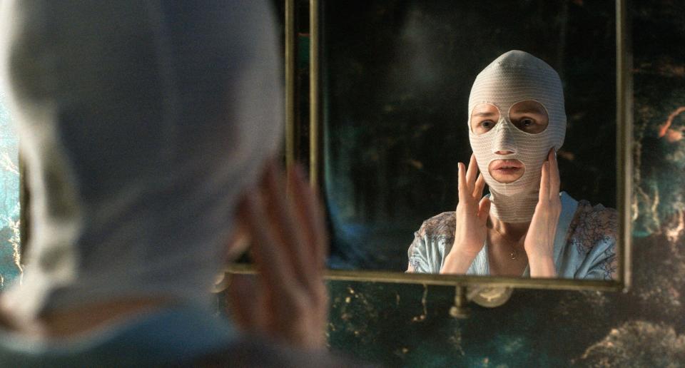 A woman rebuilding her face examines her mask in the mirror in “Goodnight Mommy”