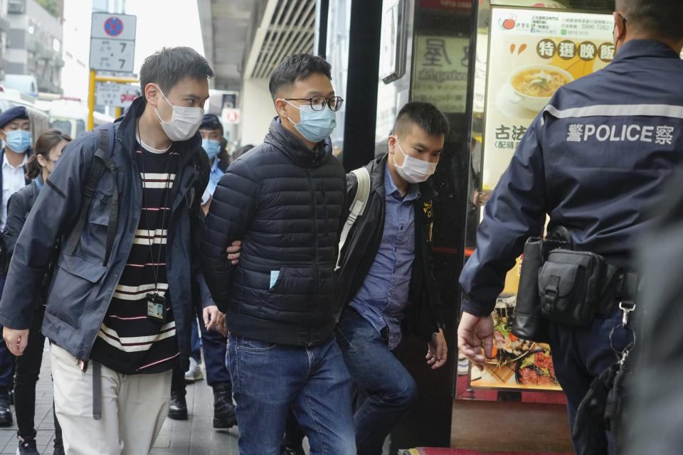 Editor of "Stand News" Patrick Lam, second from left, is arrested by police officers in Hong Kong, Wednesday, Dec. 29, 2021. Hong Kong police say they have arrested seveal current and former staff members of the online media company for conspiracy to publish a seditious publication. (AP Photo/Vincent Yu)