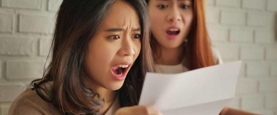 frustrated, shocked women looking at expensive bill or debt notice invoice