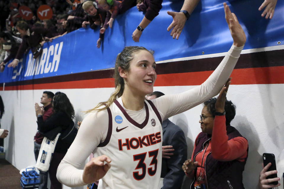 Virginia Tech's Elizabeth Kitley (33) high-fives fans after a second-round college basketball game in the women's NCAA Tournament, Sunday, March 19, 2023, in Blacksburg, Va. Even the handful of players selected in the upcoming WNBA draft will find it difficult to continue their pro careers. Kitley is thinking twice about leaving college, where they enjoy various amenities due to Title IX, including taking charter flights vs flying commercial. (AP Photo/Matt Gentry)