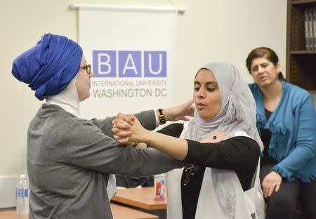 Egyptian-American community activist Rana Abdelhamid (C) demonstrates a move to student Kristin Garrity Sekerci during a self-defense workshop designed for Muslim women in Washington, DC, March 4, 2016 in this handout photo provided by Rawan Elbaba. Picture taken March 4, 2016. REUTERS/Rawan Elbaba/Handout via Reuters