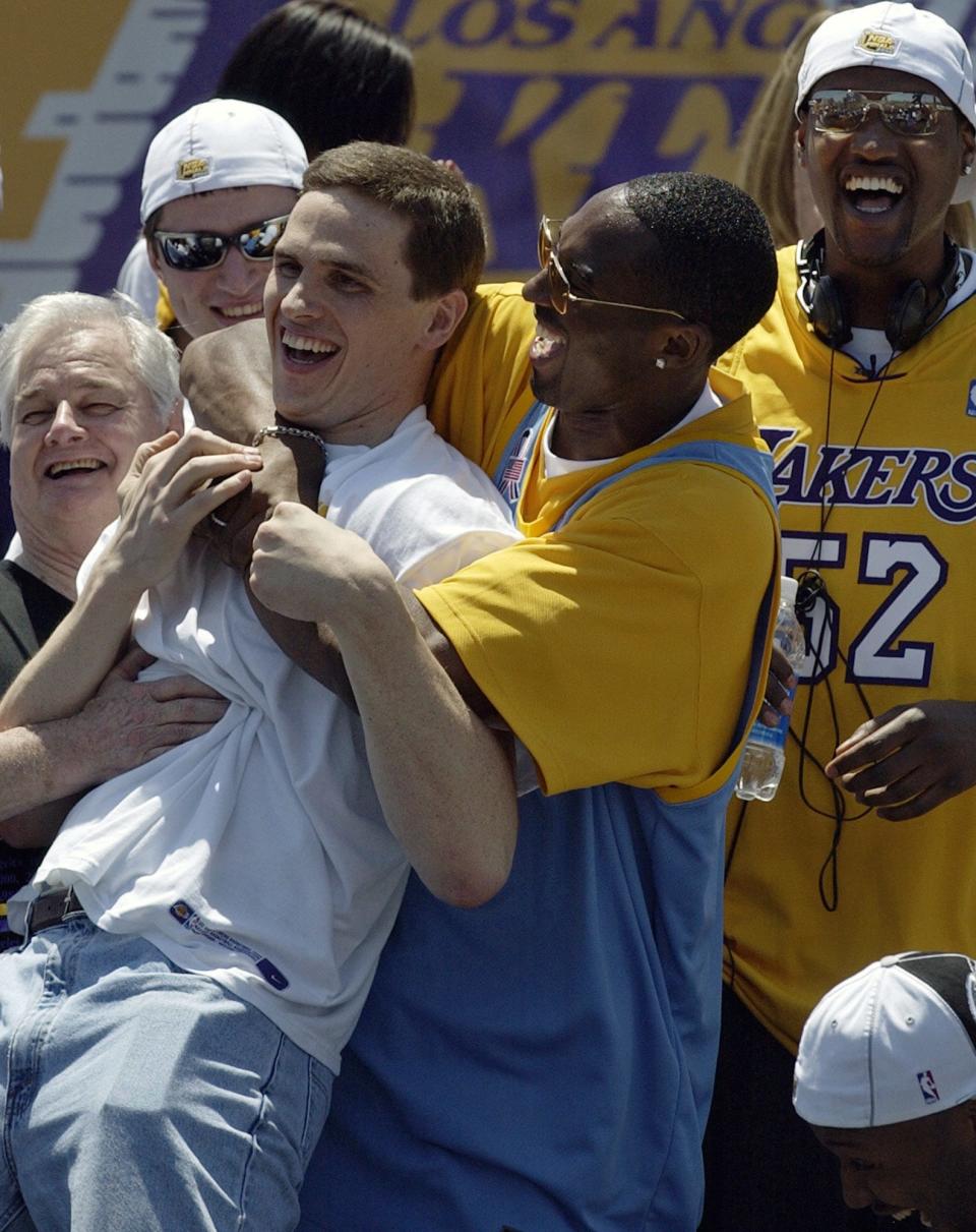 Los Angeles Lakers' Kobe Bryant, right, hugs teammate Mark Madsen after Madsen danced during the Lakers' victory celebration of their third consecutive NBA championship in 2002.