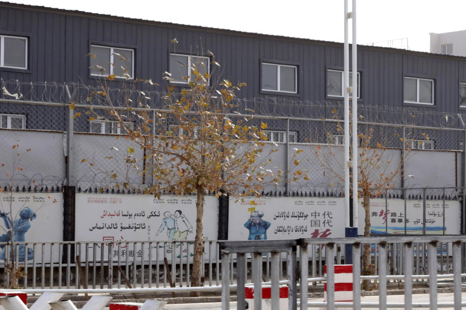 FILE - In this Dec. 5, 2018, file photo, two layers of barbed wire fencing ring the "Hotan City apparel employment training base" where clothing manufacturer Hetian Taida has a factory in Hotan in western China's Xinjiang region. A U.S. company that stocks college bookstores with t-shirts and other team apparel cut ties Wednesday, Jan. 9, 2019, with a Chinese company that drew workers from an internment camp holding targeted members of ethnic minority groups. (AP Photo/Ng Han Guan, File)