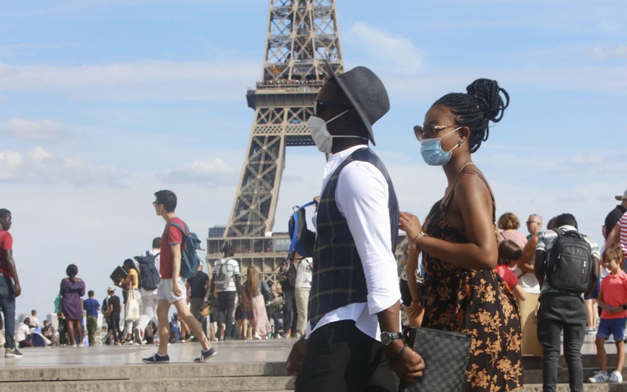 Tourists wear face masks as they walk close to the Eiffel Tower - Mehdi Taamallah/NurPhoto