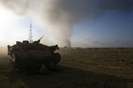 Smoke rises after an explosion in Gaza as an Israeli armoured personnel carrier (APC) is parked at a staging area near the border with Gaza July 23, 2014. REUTERS/Ronen Zvulun