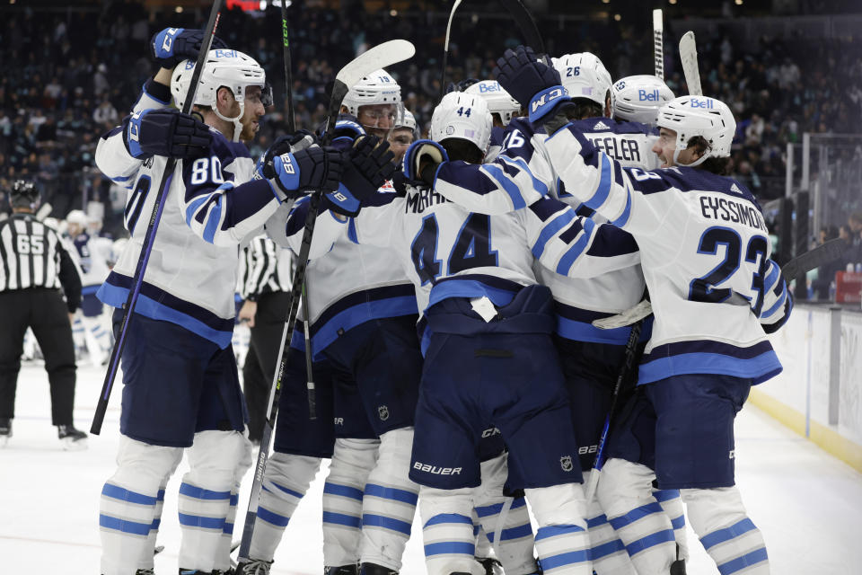 Winnipeg Jets players surround defenseman Josh Morrissey (44) while celebrating his winning goal against the Seattle Kraken during overtime period of an NHL hockey game, Sunday, Nov. 13, 2022, in Seattle. (AP Photo/John Froschauer)