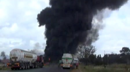 Fuel tankers queue on a road as smoke billows into air, following an explosion of a fuel tanker in Morogoro