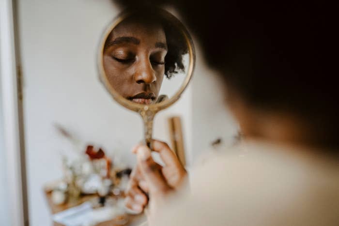 woman looking into a handheld mirror