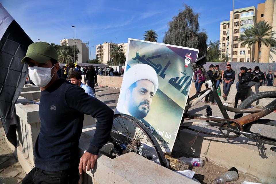 FILE - In this Jan. 1, 2020 file photo, a supporter of pro-Iranian militiamen stands by a poster of Qais al-Khazali, the leader of the militant Shiite group Asaib Ahl al-Haq, or League of the Righteous, during a sit-in in front of the U.S. embassy in Baghdad, Iraq. On Friday, Nov. 20, two Iraqi officials say Iran has instructed allies in the Middle East to be on high alert and avoid provoking tensions with the U.S. that could give an outgoing Trump Administration cause to launch attacks in his final weeks in office. (AP Photo/Khalid Mohammed, File)