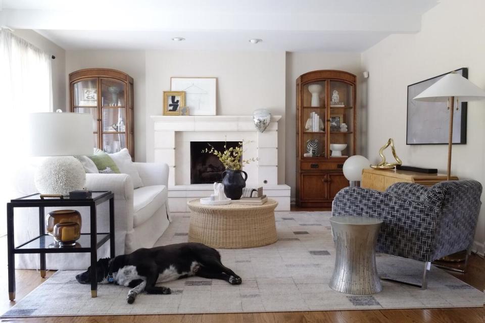 A living room by House Of Hipsters with a white stone mantle and muted textures throughout the space