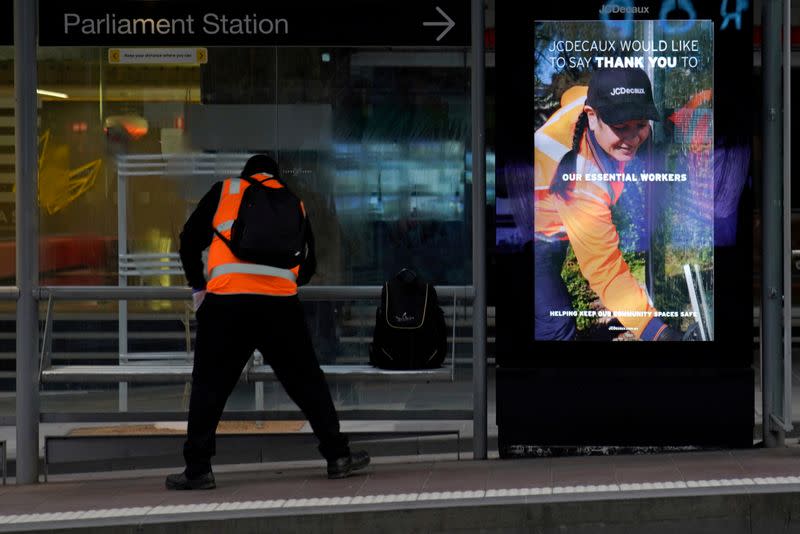 An essential worker sanitises a tram stop under COVID-19 lockdown restrictions in Melbourne