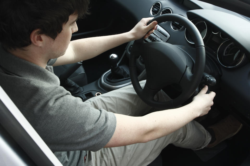 Young man turning the key in a modern car with black interior.