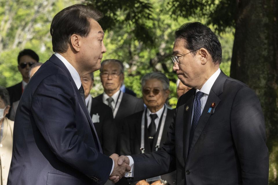 South Korea's President Yoon Suk Yeol, left, and Japan's Prime Minister Fumio Kishida shake hands during a visit to the Monument in Memory of the Korean Victims of the A-bomb near the Peace Park Memorial in Hiroshima, western Japan Sunday, May 21, 2023, on the sidelines of the G7 Summit Leaders' Meeting. (Yuichi Yamazaki/Pool Photo via AP)