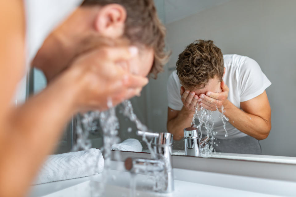 It's important to rinse your eyes immediately if experiencing any burning. (Image via Getty) Face wash man splashing water cleaning washing face with facial soap in bathroom sink. Men taking care of skin, morning face wash routine for cleaning acne pimples.