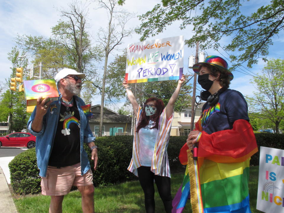 Brian Kaufman, left, Charlie Milana, center, and Emily Crowley, right, of the Philly Metro Activism Network conduct a protest in Neptune N.J., Friday, May 7, 2021, against a school vice principal who was filmed tossing beer at people who were videotaping his wife's rant against a transgender woman's use of a public restroom at an outdoor restaurant in Galloway Township N.J. in April. (AP Photo/Wayne Parry)