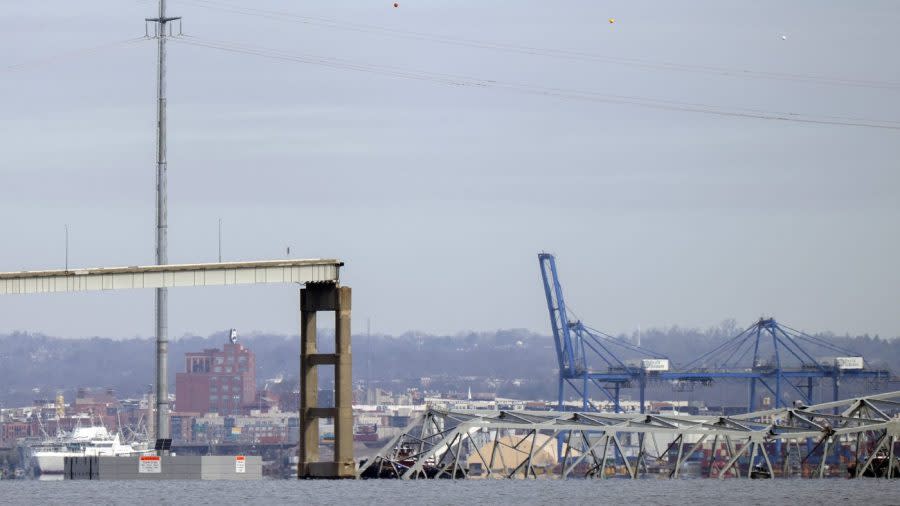 A collapsed span of the Francis Scott Key Bridge sits in the water on Tuesday, March 26, 2024, as seen from Pasadena, Md. A container ship rammed into a major bridge in Baltimore early Tuesday, causing it to collapse in a matter of seconds and creating a terrifying scene as several vehicles plunged into the chilly river below. (AP Photo/Mark Schiefelbein)