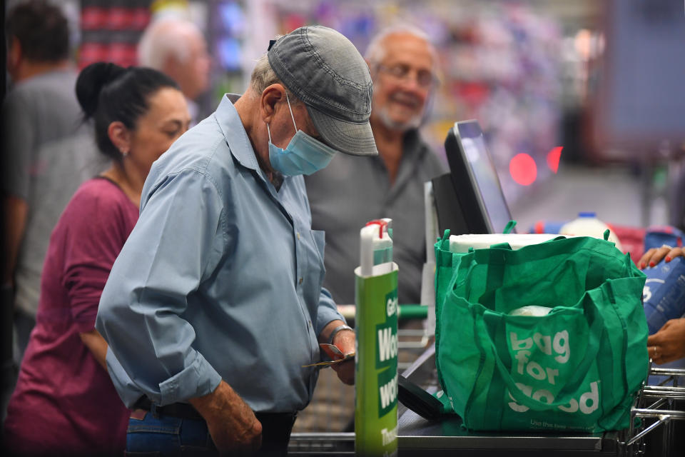 A man wears a face mask as a preventative measure against corona virus at a checkout in a Woolworths supermarket.