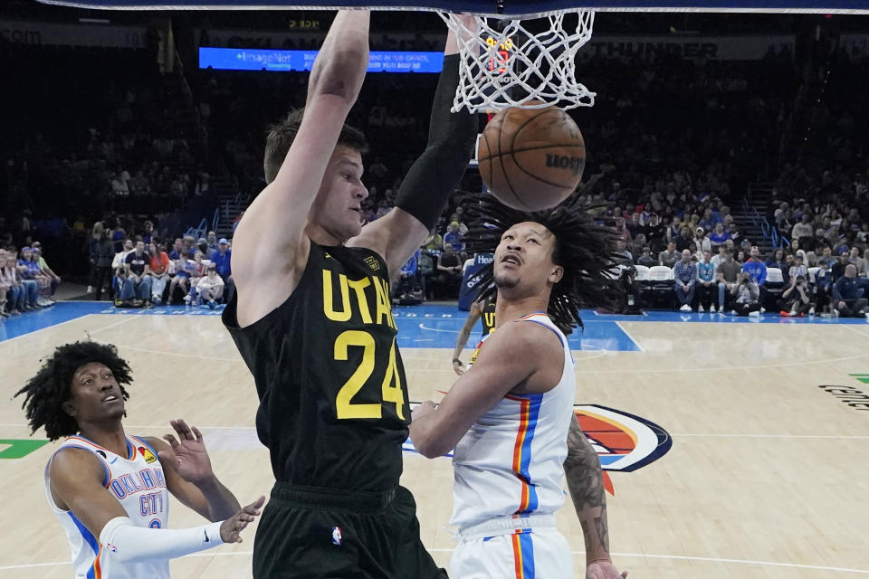 Utah Jazz center Walker Kessler (24) dunks between Oklahoma City Thunder forward Jalen Williams, left, and forward Jaylin Williams, right, in the first half of an NBA basketball game Sunday, March 5, 2023, in Oklahoma City. (AP Photo/Sue Ogrocki)