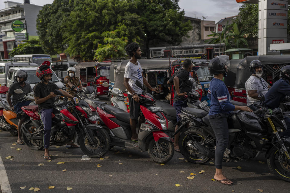 Sri Lankans wait in queue to buy petrol at a fuel station, in Colombo, Sri Lanka, July 17, 2022. Bankruptcy has forced the island nation's government to a near standstill. Parliament is expected to elect a new leader Wednesday, paving the way for a fresh government, but it is unclear if that's enough to fix a shattered economy and placate a furious nation of 22 million that has grown disillusioned with politicians of all stripes. (AP Photo/Rafiq Maqbool)