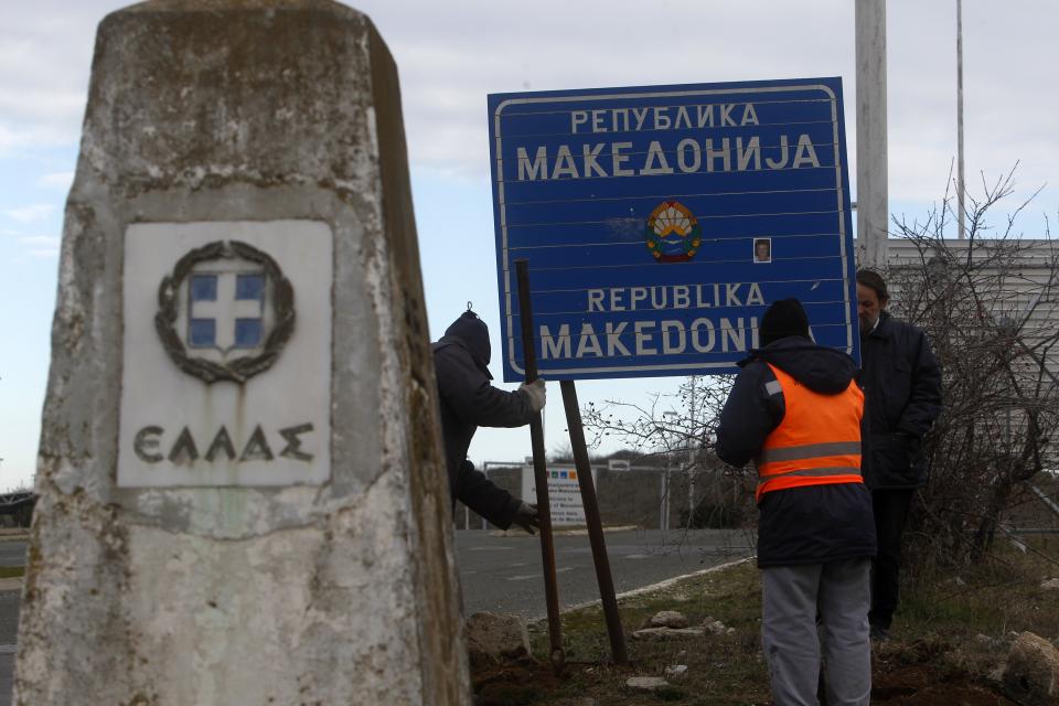 Workers remove a road sign that reads ''Republic of Macedonia'' as the other sign reads in Greek "Hellas-Greece" in the southern border with Greece, near Gevgelija, Wednesday, Feb. 13, 2019. The small Balkan country of Macedonia officially changed its name Tuesday by adding a geographic designation that ends a decades-old dispute with neighboring Greece and secures its entry into NATO. (AP Photo/Boris Grdanoski)