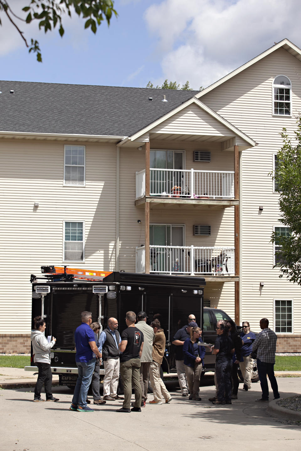 Investigators stand outside the Bluemont Village Apartments, Saturday, July 15, 2023, in Fargo, N.D. The suspect in a fatal shooting a day earlier involving local police officers was connected to at least one apartment unit at this location. Both the suspect and one police officer were killed. (AP Photo/Ann Arbor Miller)