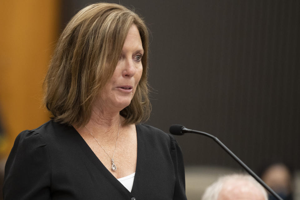 Kris Pedretti reads a statement at the podium as Joseph James DeAngelo is in the court room during the first day of victim impact statements at the Gordon D. Schaber Sacramento County Courthouse on Tuesday, Aug. 18, 2020, in Sacramento, Calif. Pedretti was 15 years old when DeAngelo broke into her Carmichael, Calif., home and raped her. DeAngelo, a former police officer in California eluded capture for four decades. He has admitted to 13 murders and nearly 50 rapes between 1975 and 1986. (Santiago Mejia/San Francisco Chronicle via AP, Pool)