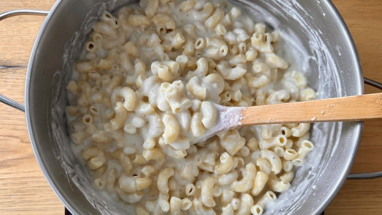 stirring pasta in cheesy sauce