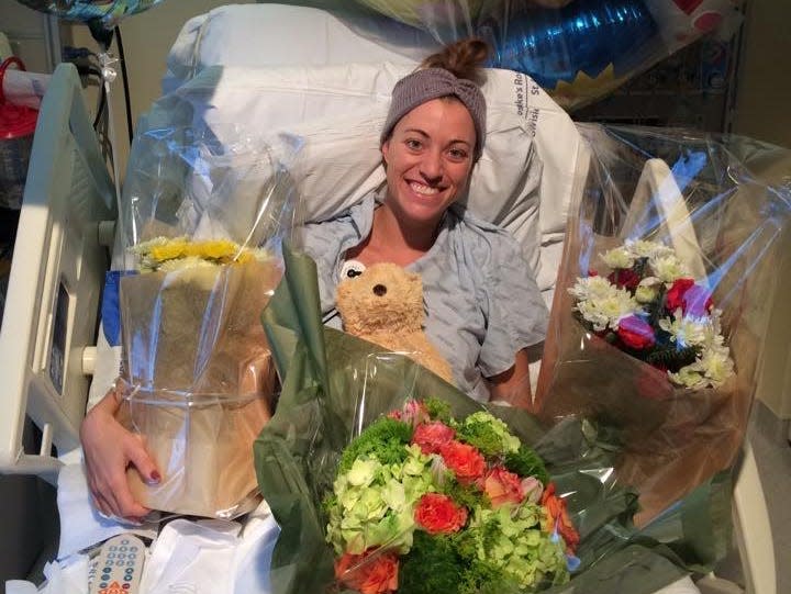 Brittany Williams surrounded by balloons and flowers in hospital bed