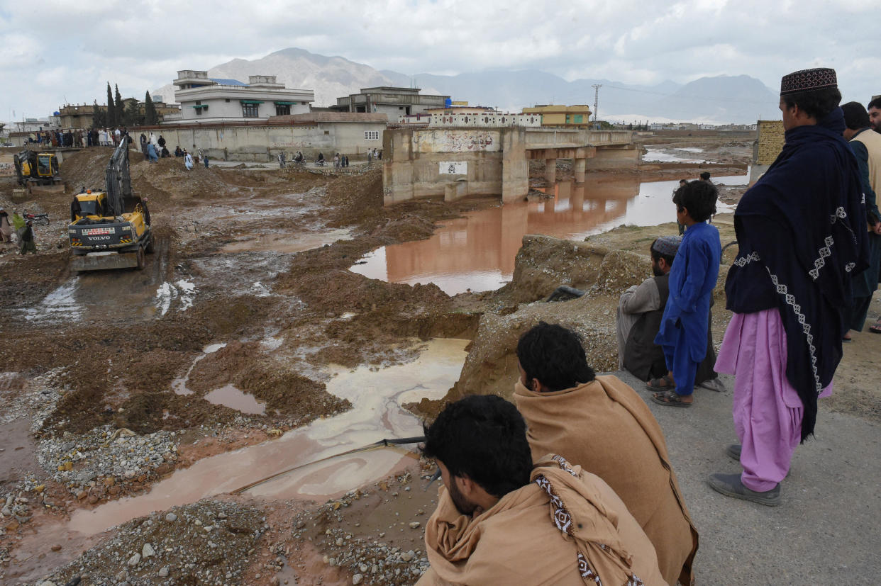Onlookers gaze towards municipal workers using heavy machinery to level the ground after damage due to floodwaters following heavy rains on the outskirts of Quetta on April 15, 2024. / Credit: BANARAS KHAN/AFP/Getty