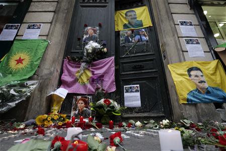 Flags, flowers and candles displayed by members of the Kurdish community are seen in front of the entrance of the Information Centre of Kurdistan in Paris, where three Kurdish women were found shot dead, January 11, 2013. REUTERS/Christian Hartmann/Files